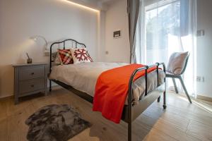 1 dormitorio con 1 cama con manta naranja y ventana en Maison Altea, en Courmayeur