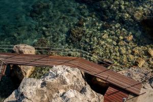 einen hölzernen Gehweg auf einer Klippe in der Nähe des Wassers in der Unterkunft Apartments Eneida in Ulcinj