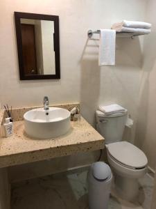 a bathroom with a sink and a toilet and a mirror at Hotel Boutique Bugambilias in Valladolid