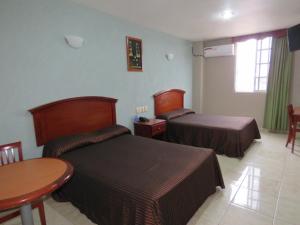 a hotel room with two beds and a table at Hotel San Juan Centro in Villahermosa