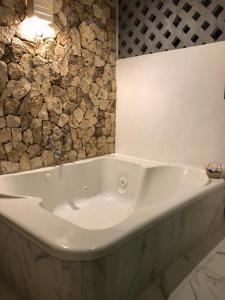 a white bath tub in a bathroom with a stone wall at Hotel Boutique Bugambilias in Valladolid
