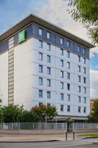 a large white building with a green sign on it at Ibis Styles Paris Gennevilliers in Gennevilliers
