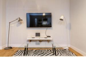 ein Wohnzimmer mit einem Tisch und einem TV an der Wand in der Unterkunft Old bilbao Con Vistas a la Ria by Urban Hosts in Bilbao