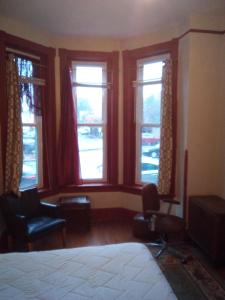 ein Schlafzimmer mit Fenstern sowie einem Bett und Stühlen in der Unterkunft Orange Wildflowers in Richmond