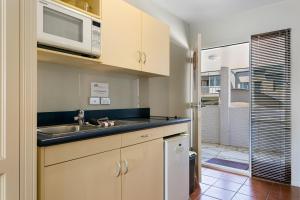 a kitchen with a sink and a microwave at Baycrest Thermal Lodge in Taupo