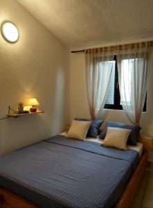 Schlafzimmer mit einem Bett mit blauer Bettwäsche und einem Fenster in der Unterkunft Apartments Amazing Sunset 100m from Sea in Ždrelac