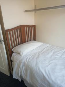 uma cama com lençóis brancos e uma cabeceira em madeira em Summerhill, Wrexham - Key Worker friendly em Wrexham