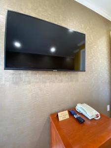 TV de pantalla plana colgada en una pared con mando a distancia en Ritz Inn-San Francisco Airport SFO, en San Bruno