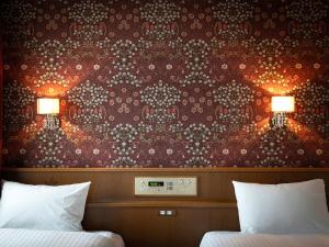 1 dormitorio con 2 camas y pared con papel pintado en Hotel Eclair Hakata, en Fukuoka