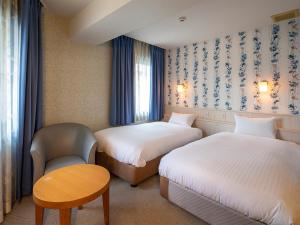 a hotel room with two beds and a table and a chair at Hotel Eclair Hakata in Fukuoka