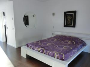 Cama en habitación blanca con manta morada en Villa Silva, en Armação de Pêra