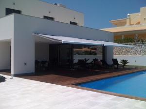 Casa blanca con piscina y patio con toldo en Villa Silva, en Armação de Pêra