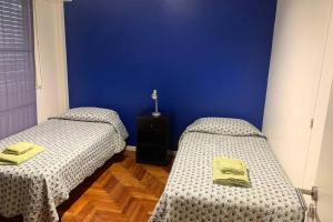 Duas camas num quarto com uma parede azul em Best location in Caballito, Buenos Aires, 80 M2 em Buenos Aires