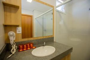 um balcão de casa de banho com um lavatório e um espelho em Tri Hotel Chapecó em Chapecó