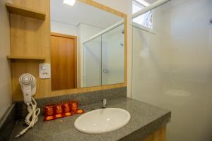 a bathroom counter with a sink and a mirror at Tri Hotel Chapecó in Chapecó