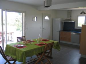 a kitchen with a table with a green table cloth at Les Romarins in Aigne