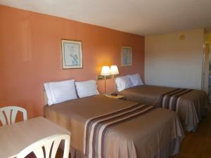 2 bedden in een hotelkamer met oranje muren bij Americas Best Value Inn Tucker in Tucker