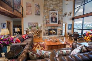 a living room with leather furniture and a stone fireplace at Spring Creek Ranch in Jackson
