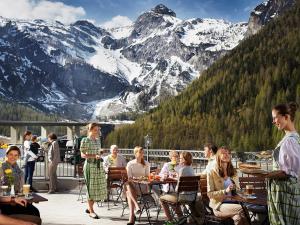 a group of people sitting at tables on a deck with mountains at Landzeit Tauernalm in Flachau