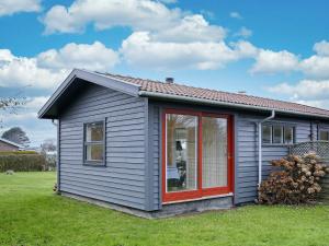 una pequeña casa gris con una puerta roja en 4 person holiday home in Svendborg en Svendborg