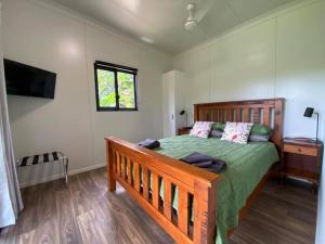 a bedroom with a wooden bed with a green comforter at Mena Creek Flower House in Mena Creek