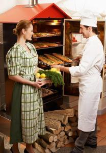 a man and woman standing in a kitchen preparing food at Landzeit Autobahn-Restaurant Steinhäusl bei Wien in Altlengbach