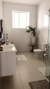 a bathroom with a sink and a toilet and a window at Hostel Tropeiro de Minas in Juiz de Fora