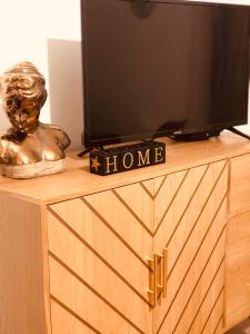 a television on top of a wooden dresser with a statue at Le studio d'Angèle : Angie in Bruz