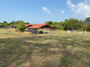 un granero con techo rojo en un campo en Hotel - Granja de Animales San Basilio de Palenque, en San Basilio del Palenque