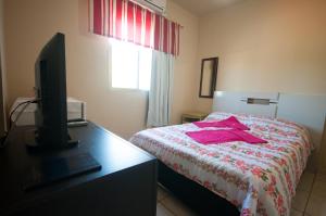 a bedroom with a bed with a dresser and a television at Pousada Jomar in Xangri-lá