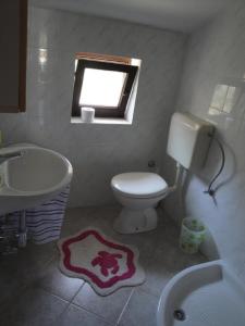 ein Bad mit einem WC, einem Waschbecken und einem Fenster in der Unterkunft Apartments Niki - 5m from the sea in Drvenik Veli