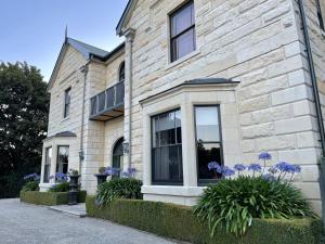 a stone house with purple flowers in front of it at Casa Nova House in Oamaru