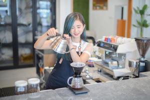 a woman standing behind a counter with a blender at Petik Merah Homestay in Yogyakarta