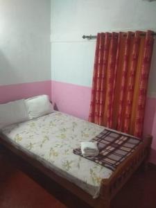 a small bed in a room with a curtain at green valley home stay vagamon in Vagamon