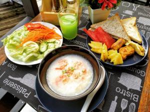 a table with two plates of food and a bowl of soup at Hotel De Nara in Chiang Mai