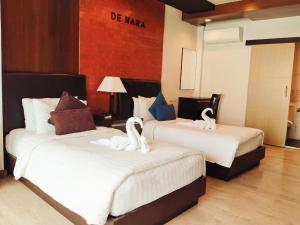 dwa łabędzie siedzące na dwóch łóżkach w pokoju hotelowym w obiekcie Hotel De Nara-SHA Extra Plus w mieście Chiang Mai