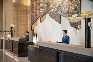 two people sitting at a reception desk in a lobby at InterContinental Foshan DongPing in Shunde
