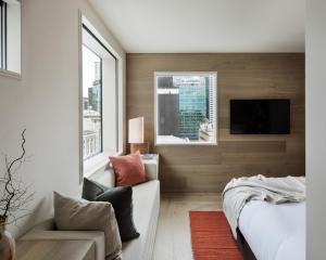 a bedroom with a couch and a tv and a window at The Hotel Britomart in Auckland
