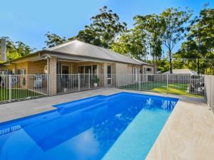 a swimming pool in front of a house at Sun Daze at Smithies in Smiths Lake