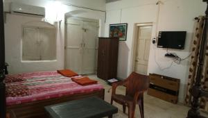 1 dormitorio con 1 cama, TV y silla en Kamat Cottages en Dāhānu