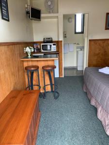 a hotel room with a bed and a kitchen and a table at New Central Hotel Woodville in Woodville