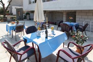 un patio con mesas, sillas y una sombrilla en Guest House Raguž, en Dubrovnik