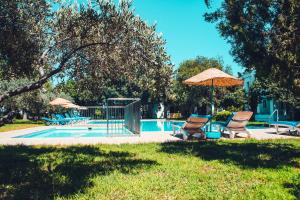 a swimming pool with two chairs and an umbrella at Muskebi Apart Otel in Ortakent