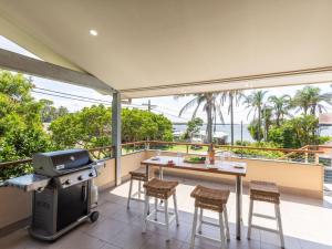 a balcony with a grill and a table and chairs at 1 Soldiers Point Road fabulous home with water views in Soldiers Point