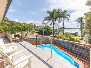 a balcony with a view of a swimming pool and palm trees at 1 Soldiers Point Road fabulous home with water views in Soldiers Point