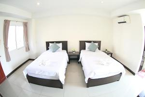 two beds in a room with white walls at วีรวรรณ เพลส Weerawan Place in Khon Kaen