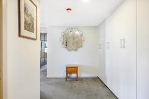 a white hallway with a clock on the wall at Jenatt Apartments Salamanca in Hobart