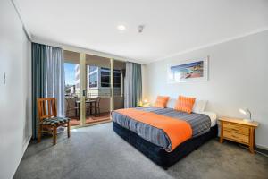 a bedroom with a bed and a balcony with a table at Jenatt Apartments Salamanca in Hobart