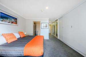a bedroom with a large bed with an orange blanket at Jenatt Apartments Salamanca in Hobart