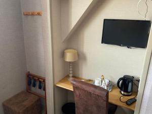 Habitación con escritorio y TV en la pared. en Les 3 rois by YY, en Villers-Bocage